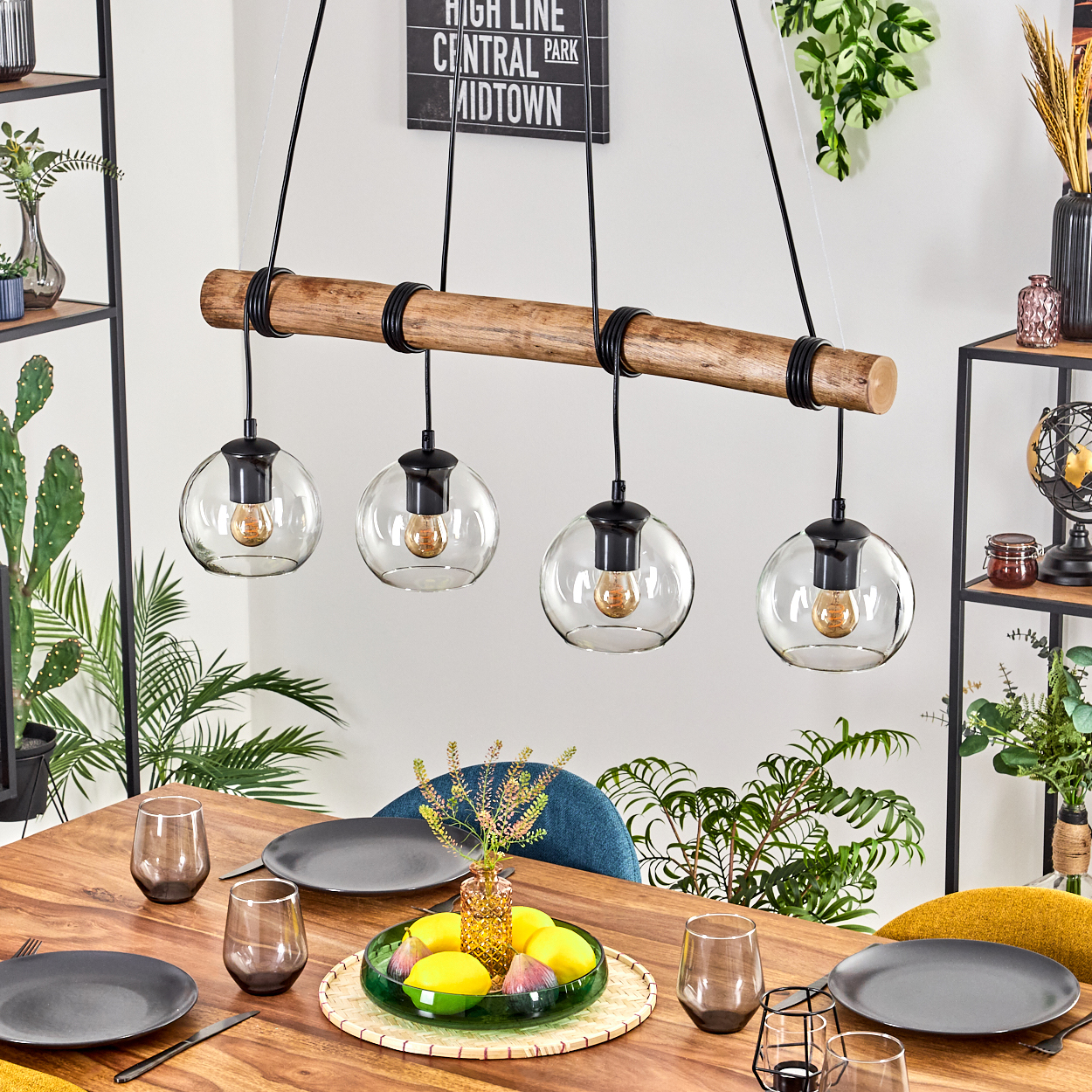 Ein Esszimmer mit Holztisch, Hängelampen und einem dekorativen Mittelstück mit Früchten.