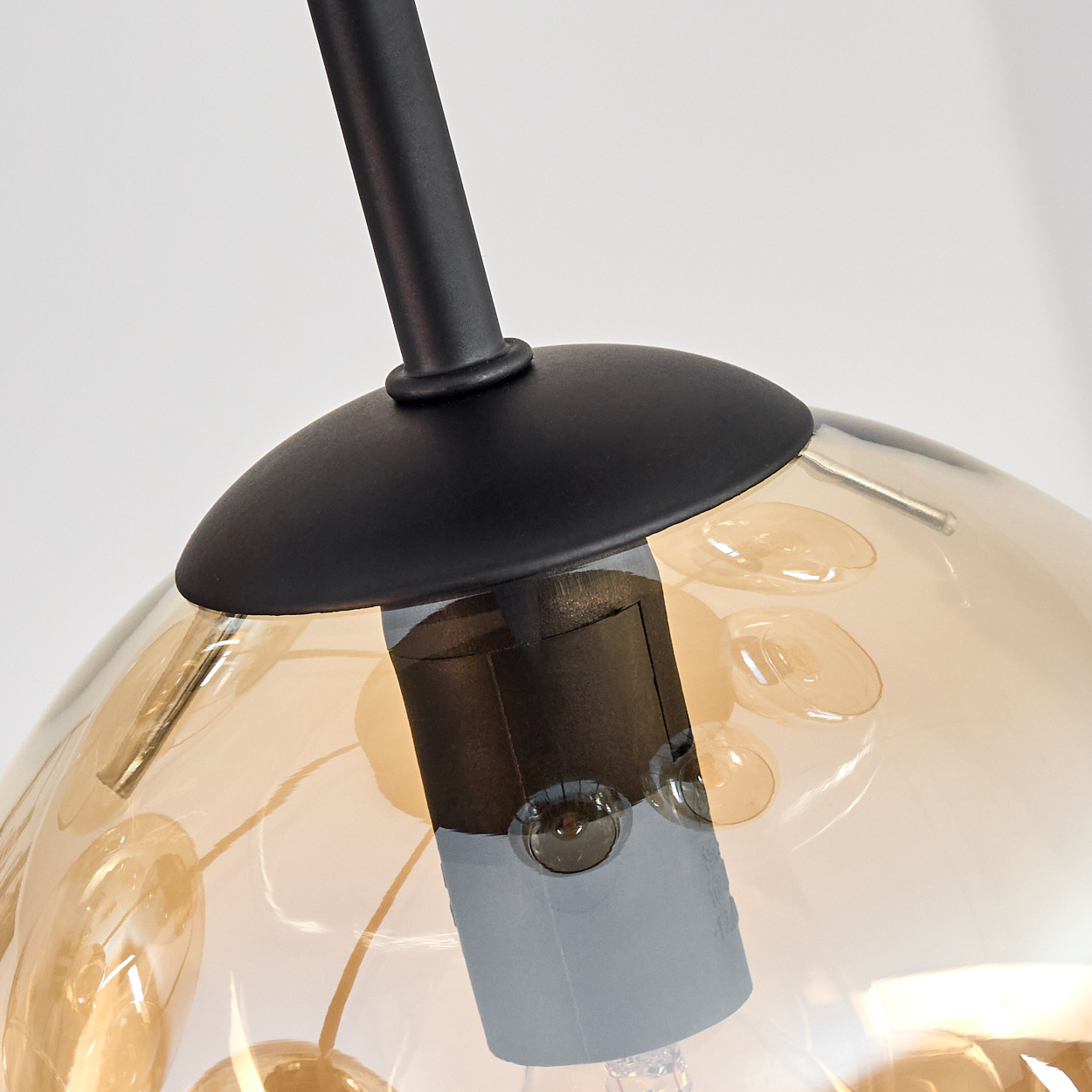 Nahaufnahme einer schwarzen Lampe mit einem Globus. Der Globus ist transparent mit bernsteinfarbenen Farbtönen und Blasen.