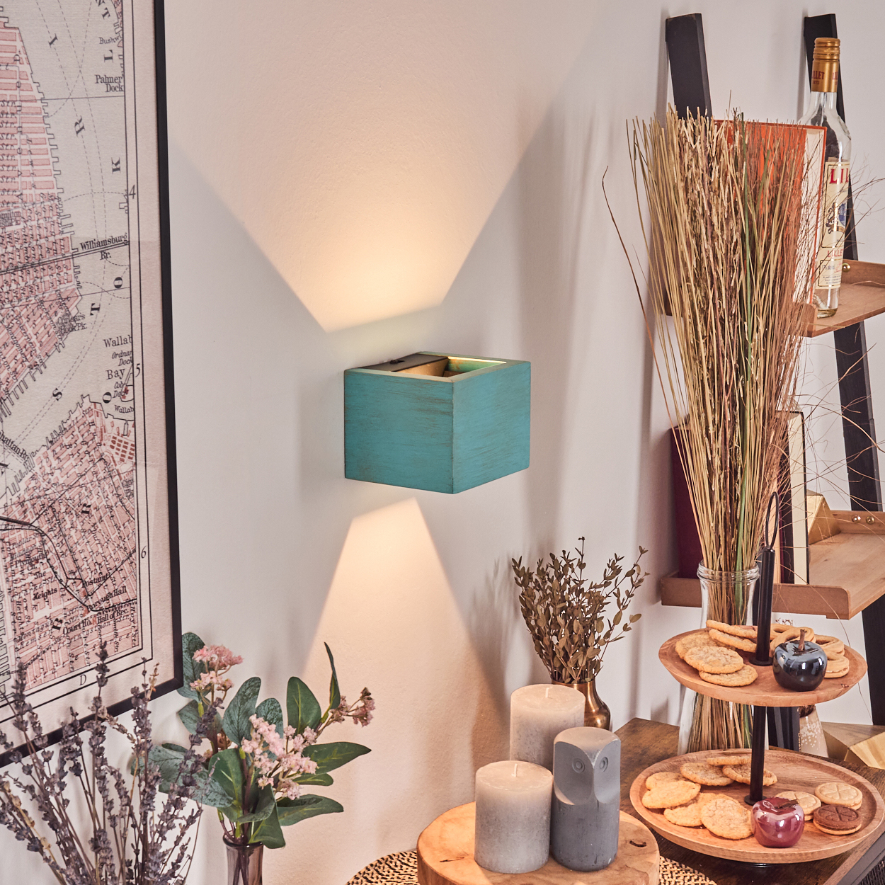 Eine türkisfarbene Wandlampe strahlt Licht aus. Eine Karte, Blumen und ein Regal mit Snacks sind in der Nähe.