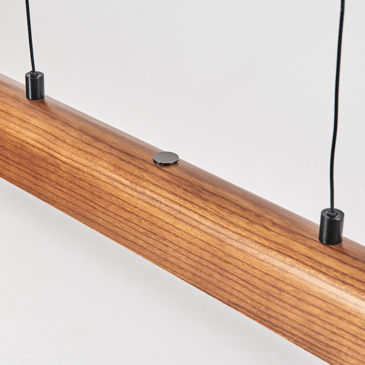 Nahaufnahme eines Holzbalkens mit zwei schwarzen Drähten und Metalldetails vor weißem Hintergrund.