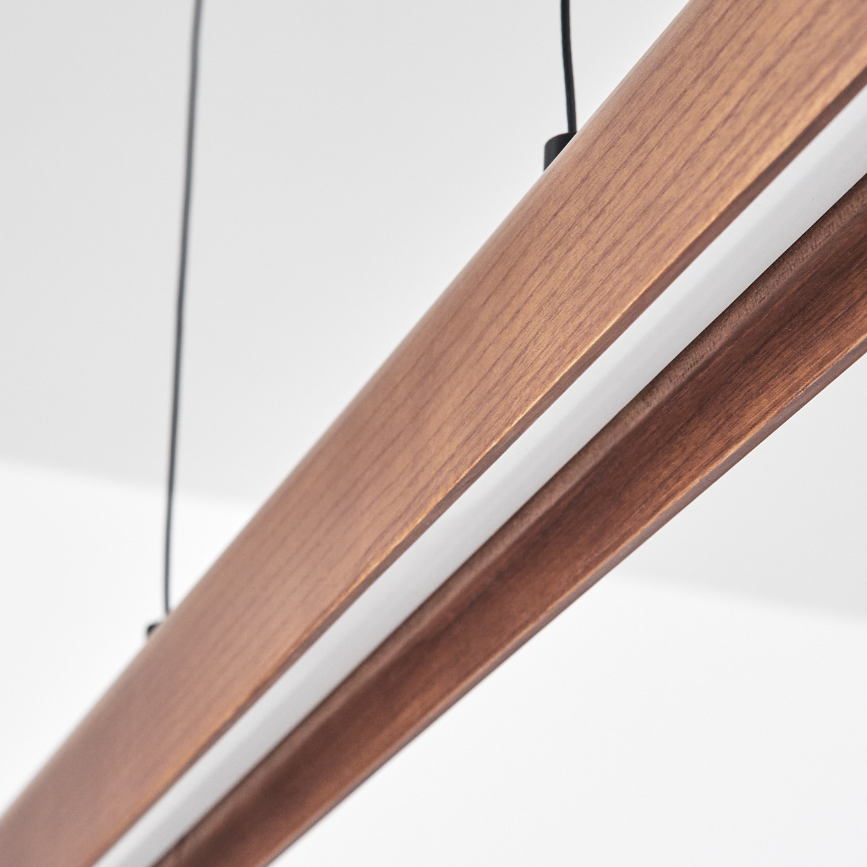 Nahaufnahme einer hölzernen Leuchte. Die Leuchte ist rechteckig, mit einem braunen Holzrahmen und einer weißen Lichtquelle.
