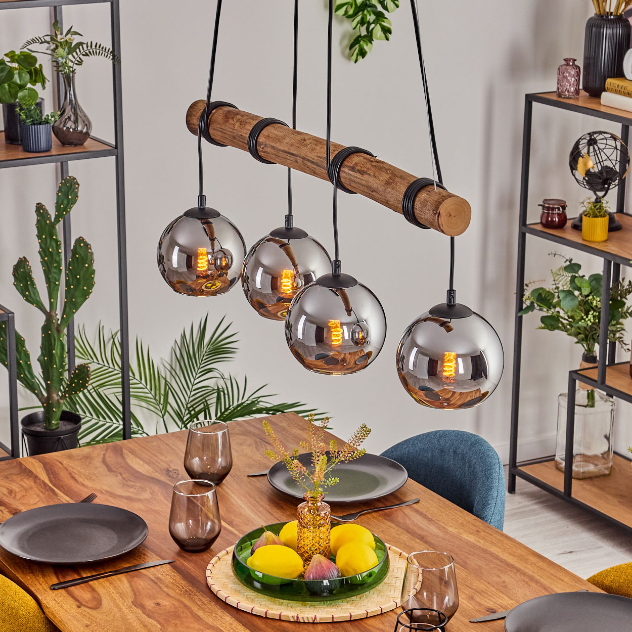 Esszimmer mit Holztisch, vier Hängelampen und Tischdeko. Obst und Gläser stehen auf dem Tisch.