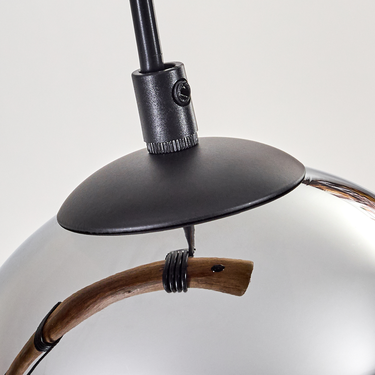 Nahaufnahme einer modernen Lampe. Sie hat einen schwarzen Deckel, einen chromähnlichen Boden und einen Holzgriff. Der Hintergrund ist weiß.