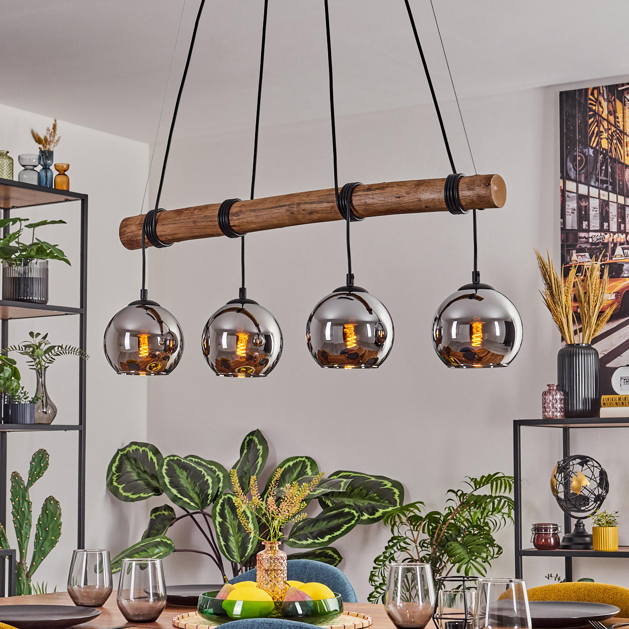 Esszimmer mit Holzbalken-Kronleuchter. Darunter Gläser, Pflanzen und ein Tisch mit Obst. Ein Stadtgemälde hängt.