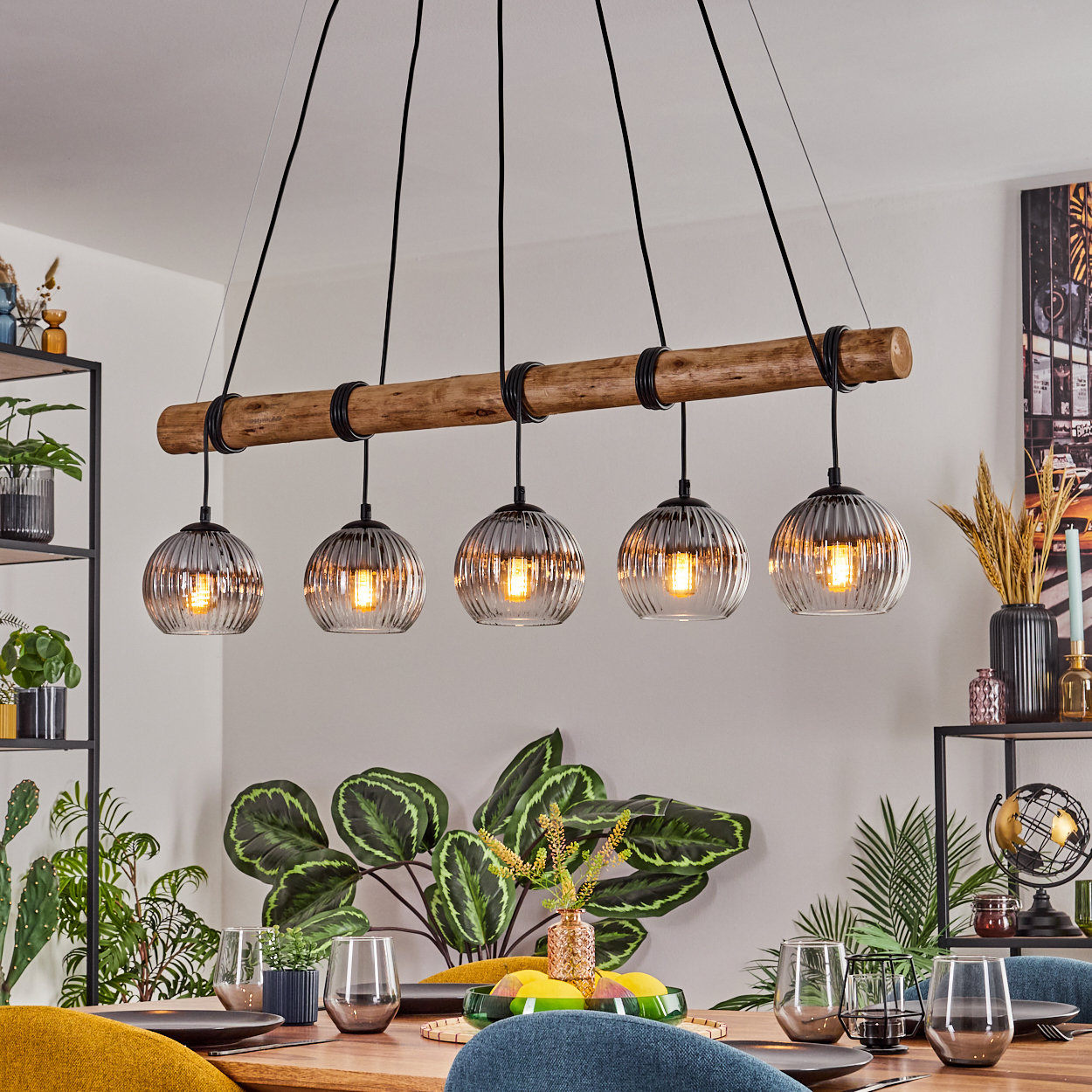 Esszimmer mit Holztisch, Pflanzen und einer Leuchte mit fünf Glaskugelleuchten.
