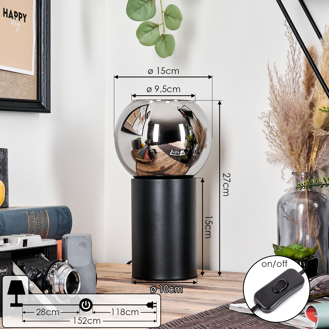 Eine moderne schwarze Lampe mit einer verspiegelten Glaskugel. Sie steht auf einem Holztisch mit anderen Gegenständen wie einer Kamera und Büchern.