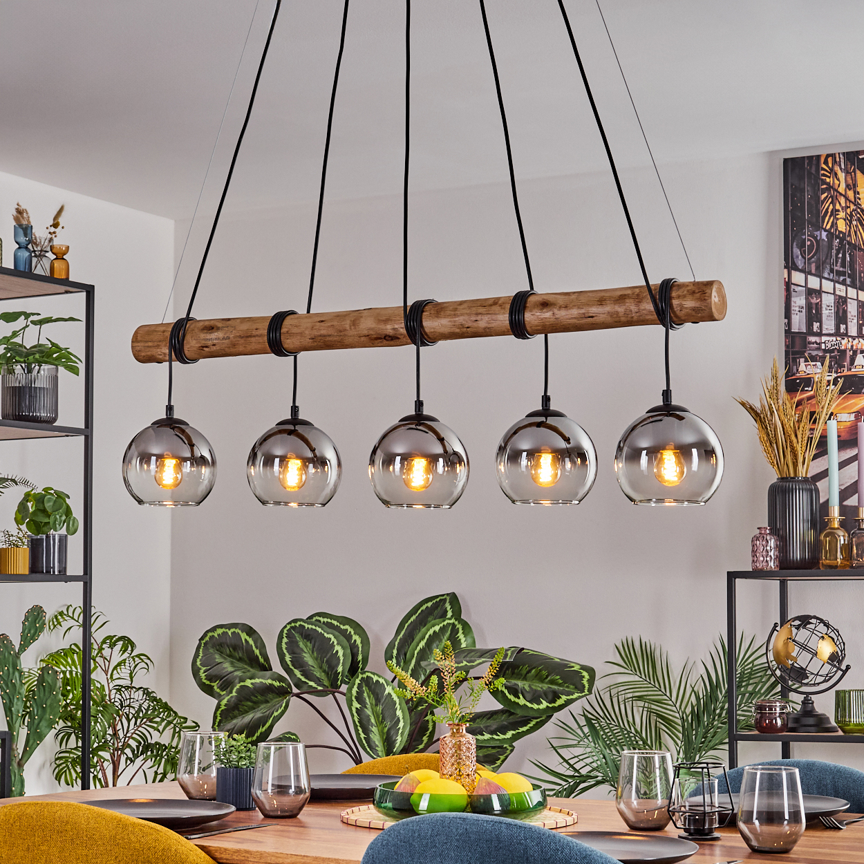 Ein Esszimmer mit Holztisch, Hängelampen, Pflanzen und Gedecken. Die Lampen haben Glaskugeln.