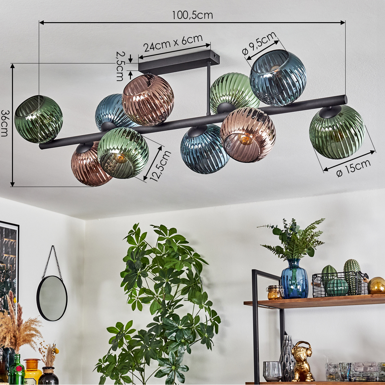 Eine moderne Deckenlampe mit farbigen Glaskugeln. Darunter eine Pflanze, ein Regal mit Dekorationen und ein Spiegel an der Wand.