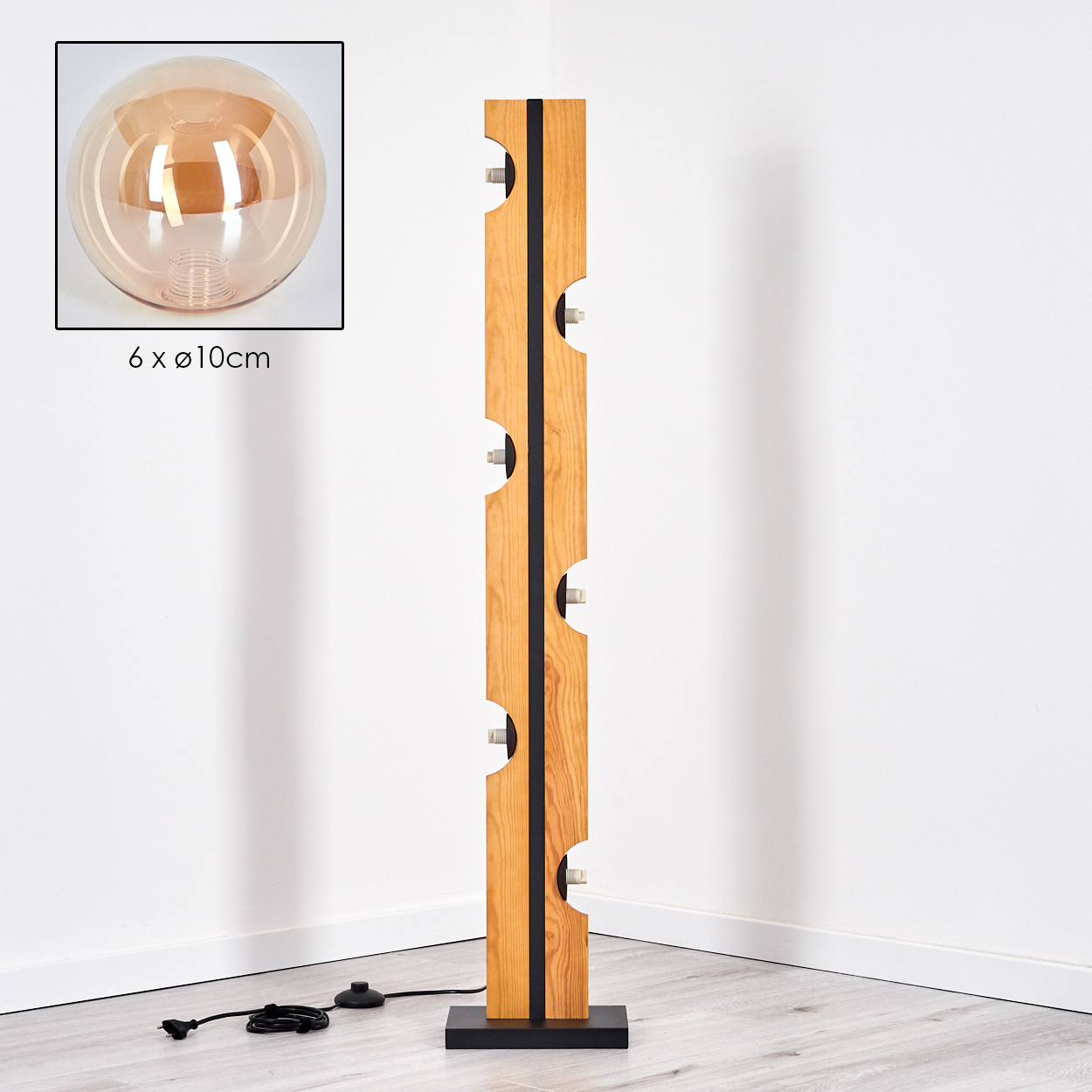 Holz-Stehlampe mit schwarzem Sockel, Holzkörper mit sechs Lampen und einer großen Glühbirne. Der Hintergrund ist eine weiße Wand.