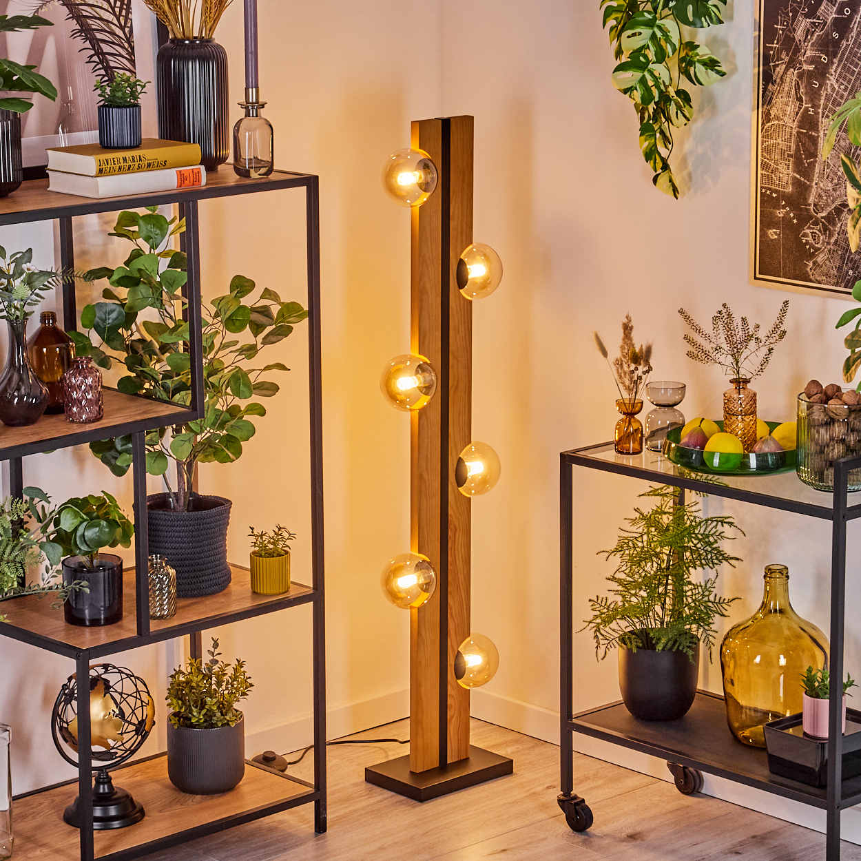 Eine moderne Wohnzimmerszene mit Stehlampe. Regale mit Pflanzen und Dekoration. Eine Karte hängt an der Wand.
