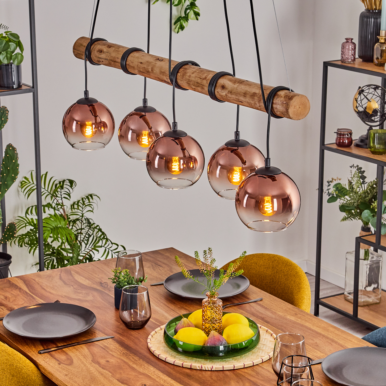 Esszimmer mit Holztisch, Kupfer-Pendelleuchten, Obst und Pflanzen. Ein moderner, einladender Raum mit warmen Tönen.