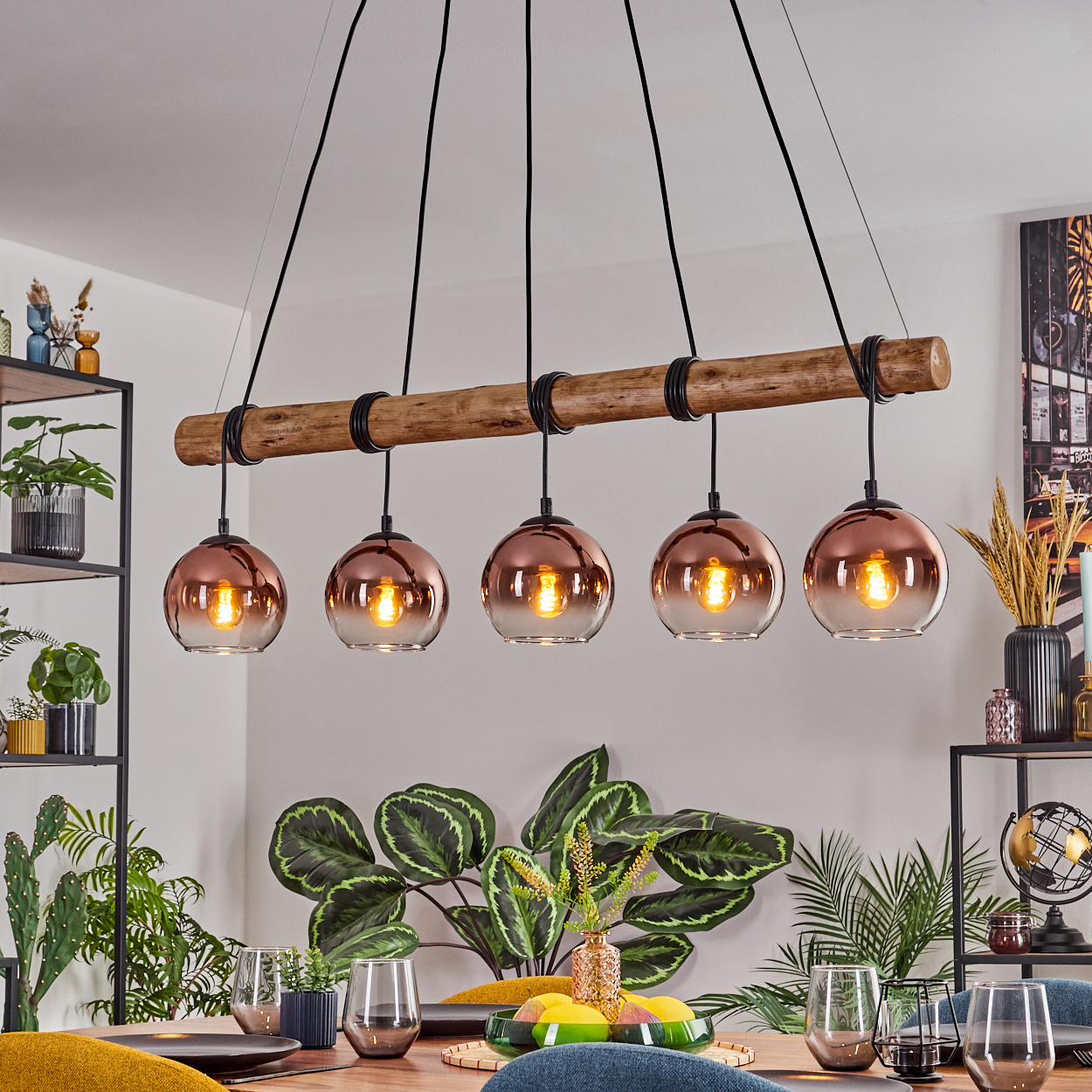 Esszimmer mit Holztisch, Pflanzen und einer Leuchte mit fünf kupferfarbenen Kugelleuchten.
