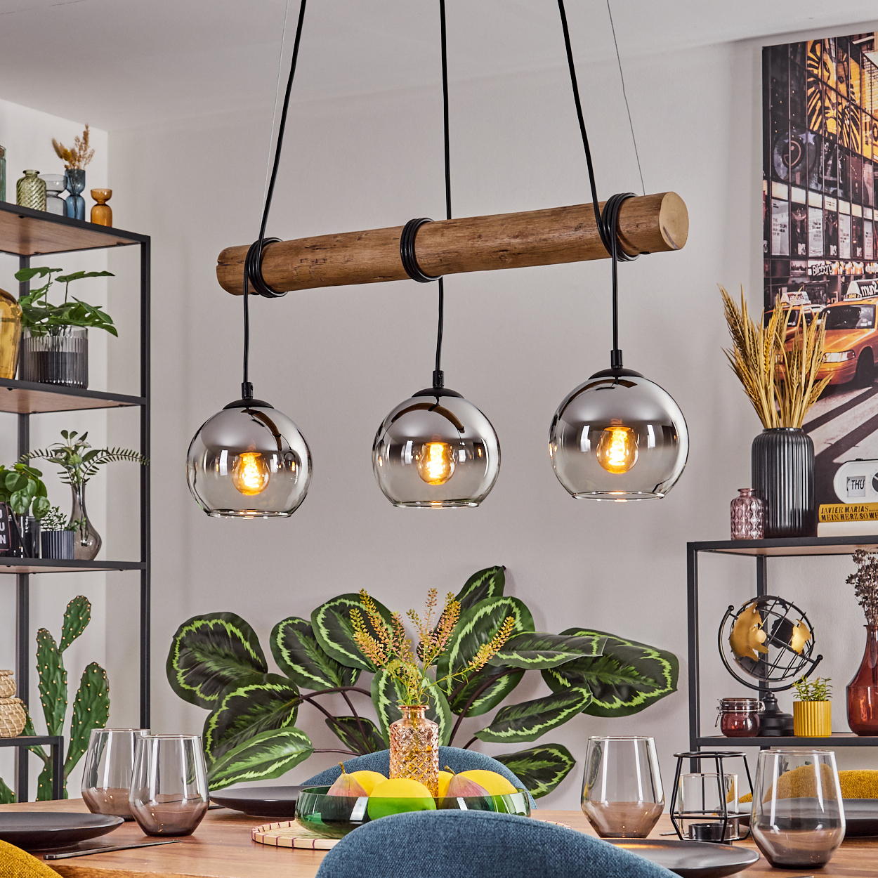 Esszimmer mit Holzbalken-Leuchte und drei Glaskugellampen. Tisch mit Gläsern und einer Pflanze gedeckt.