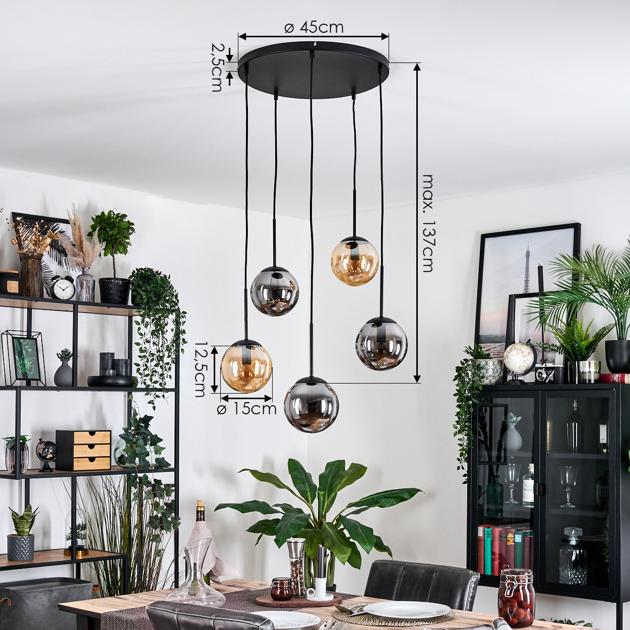 Ein modernes Esszimmer mit einem schwarzen Kronleuchter. Der Kronleuchter hat fünf hängende Glaskugeln. Pflanzen und Dekorationen füllen den Raum.