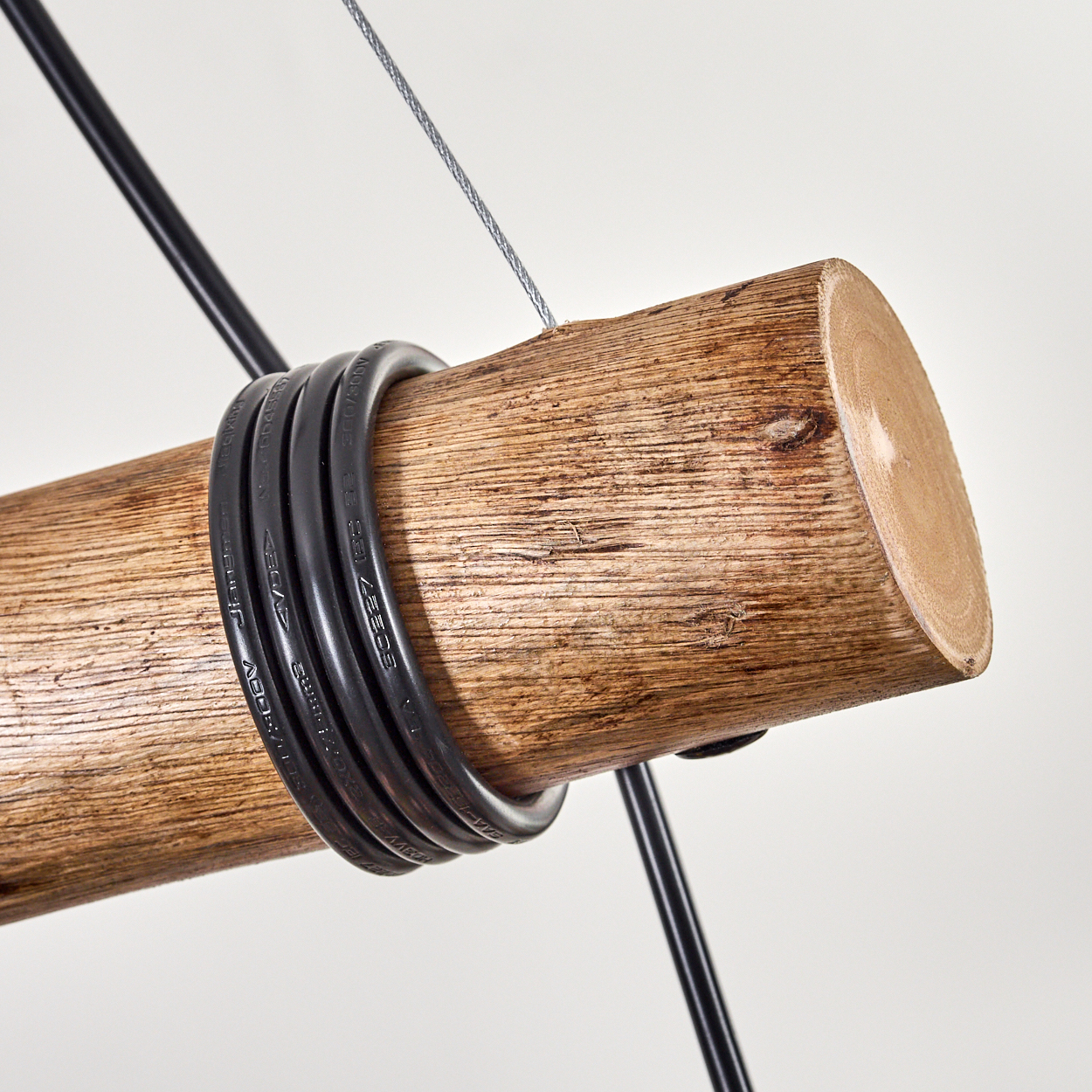 Nahaufnahme eines Holzstamms mit schwarzen Kabeln. Ein silbernes Kabel und ein schwarzer Draht gehen vor weißem Hintergrund davon aus.