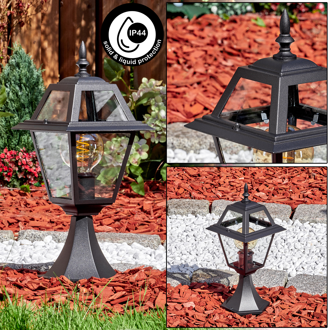 Eine schwarze Außenlampe mit Glasgehäuse. Sie steht auf einem Sockel, umgeben von roter Mulche, weißen Steinen und grünem Gras.