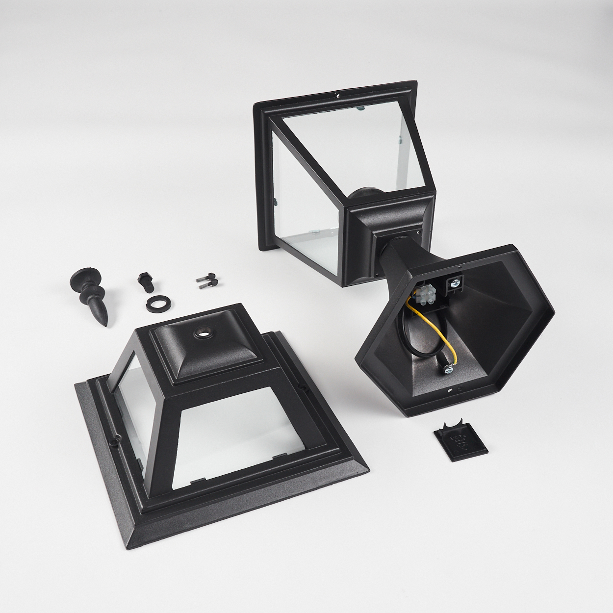 Schwarze, zerlegte Außenlampe mit Glasscheiben. Teile umfassen Basis, Oberteil, Rahmen und kleine Hardware vor weißem Hintergrund.