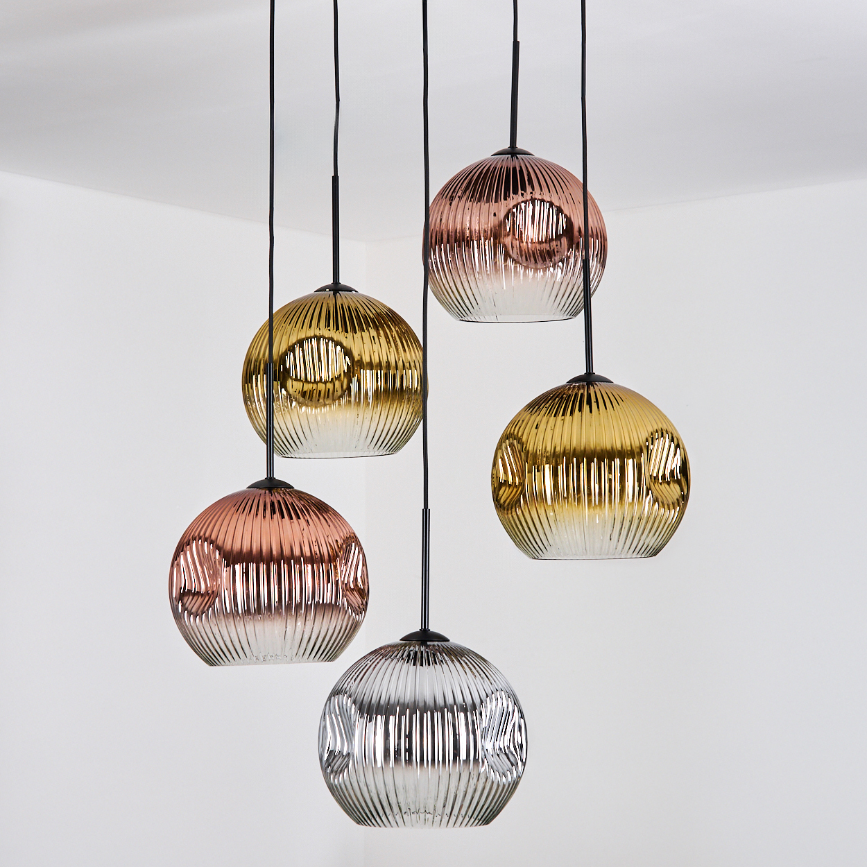 Fünf kugelförmige Pendelleuchten mit strukturierten Glasschirmen in Gold, Kupfer und Silber, die an schwarzen Schnüren hängen.