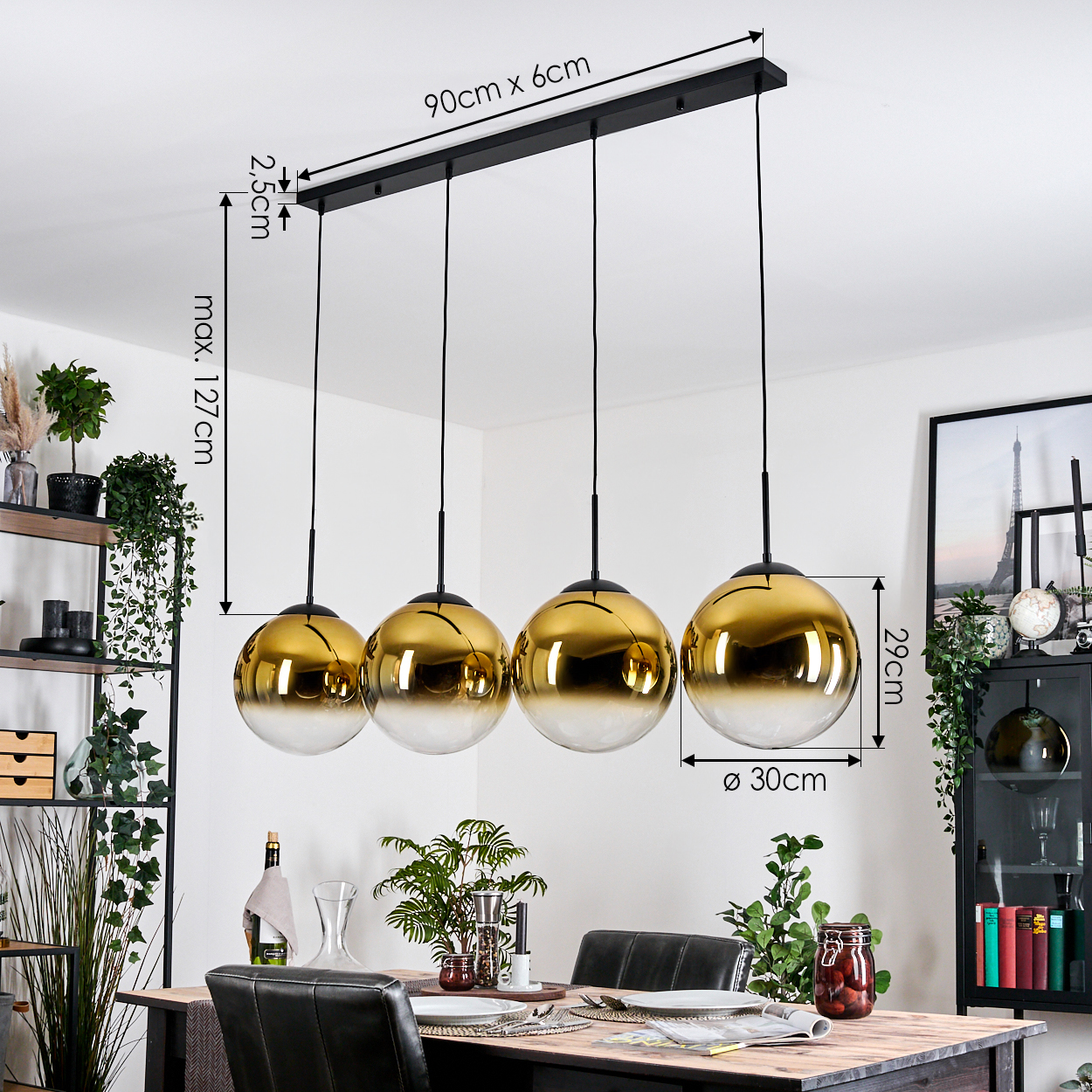 Vier goldene und klare Glaskugelleuchten hängen über einem Esstisch. Pflanzen und Dekorationen umgeben den Tisch in einem Esszimmer.