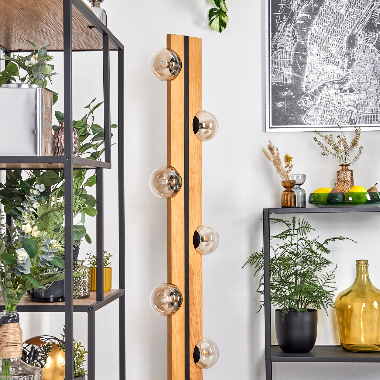 Holzlampe mit Glaskugeln, schwarze Regale mit Pflanzen, Karte an der Wand. Verschiedene Vasen und Dekorationen sind vorhanden.