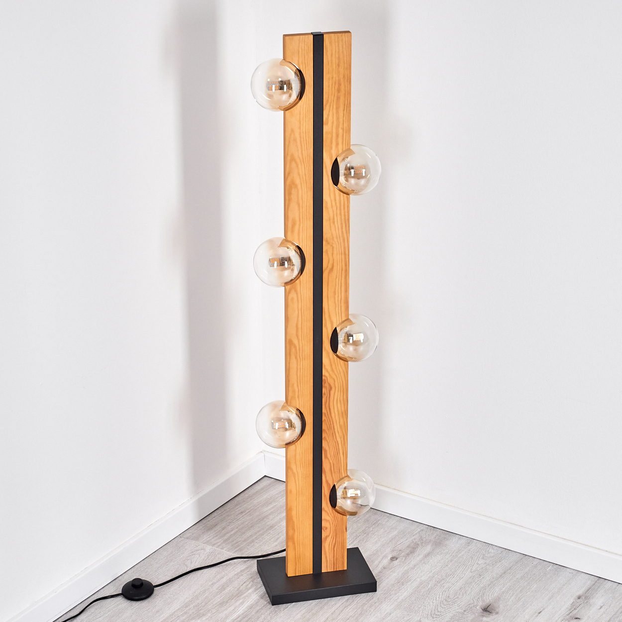 Eine moderne Stehlampe mit sechs Glühbirnen. Sie hat einen Holzrahmen, schwarze Akzente und einen schwarzen Sockel in einer Ecke.