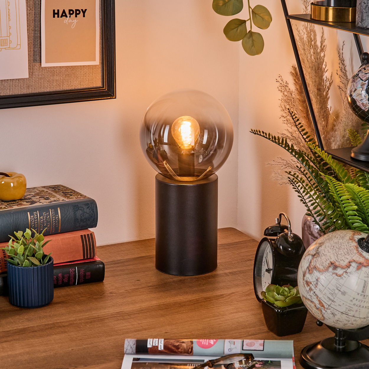 Eine leuchtende Lampe steht auf einem Holztisch mit Büchern, Pflanzen und einem Globus. Ein Schild sagt 'Happy day'.