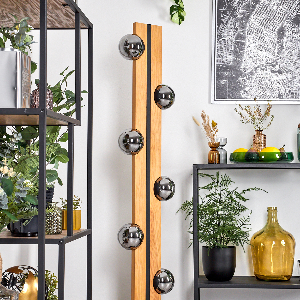 Ein modernes Interieur mit Holzpaneel und reflektierenden Kugeln. Regale mit Pflanzen, Vasen und Dekorationsartikeln. Eine Karte hängt an der Wand.