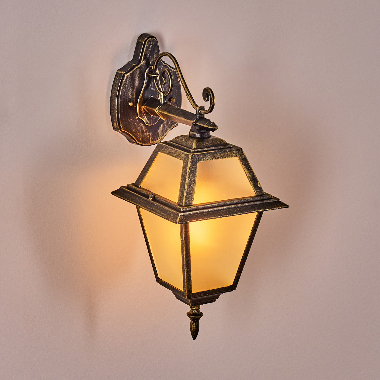 Eine Wandlampe im antiken Stil mit goldenem Rahmen und Milchglasscheiben, an einer cremefarbenen Wand montiert.