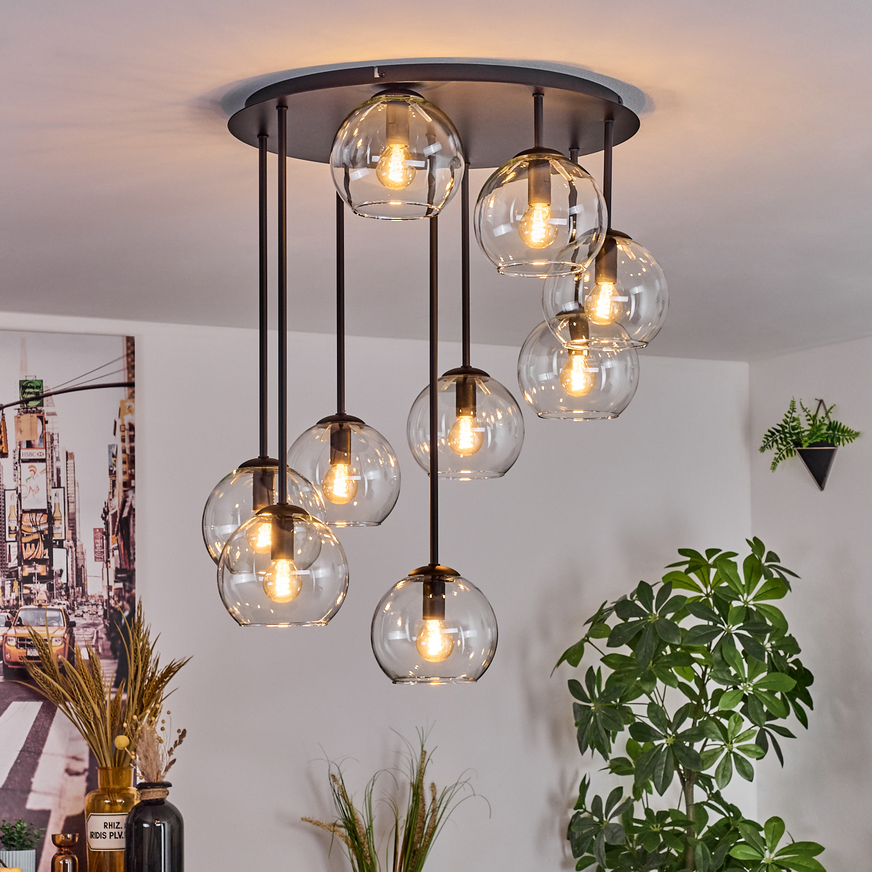 Eine moderne Deckenleuchte mit mehreren kugelförmigen Glaslichtern hängt von der Decke. Pflanzen und Stadtlandschaftskunst sind im Hintergrund.
