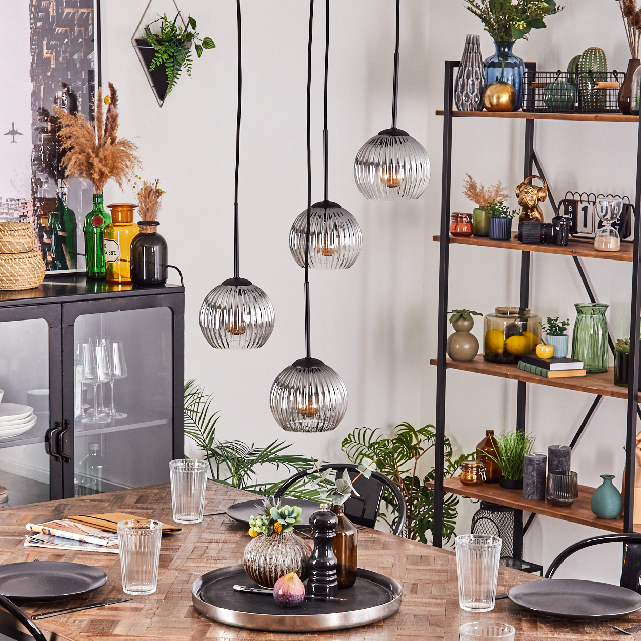 Esszimmer mit Holztisch, Glaslampen und dekorativen Regalen. Tisch mit Tellern und Gläsern gedeckt.