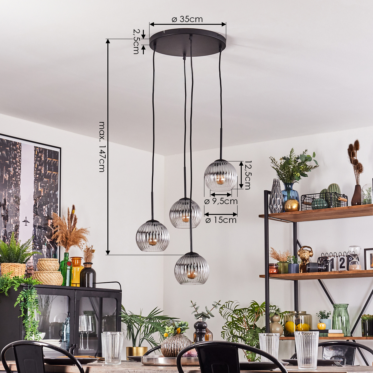 Ein modernes Esszimmer mit einem schwarzen Kronleuchter mit Glaskugeln, einem Tisch mit Gläsern und einem Regal mit Pflanzen.