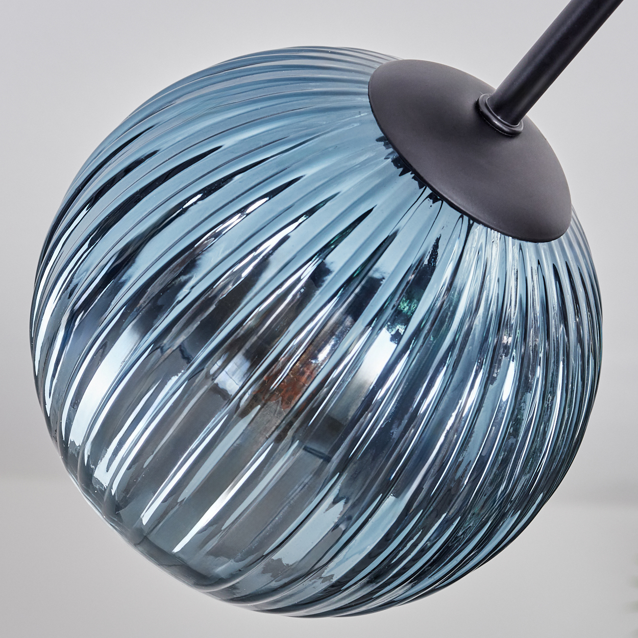 Nahaufnahme einer blauen Glaskugel-Lampe mit schwarzem Stiel. Die Kugel hat eine strukturierte Oberfläche mit horizontalen Rillen.