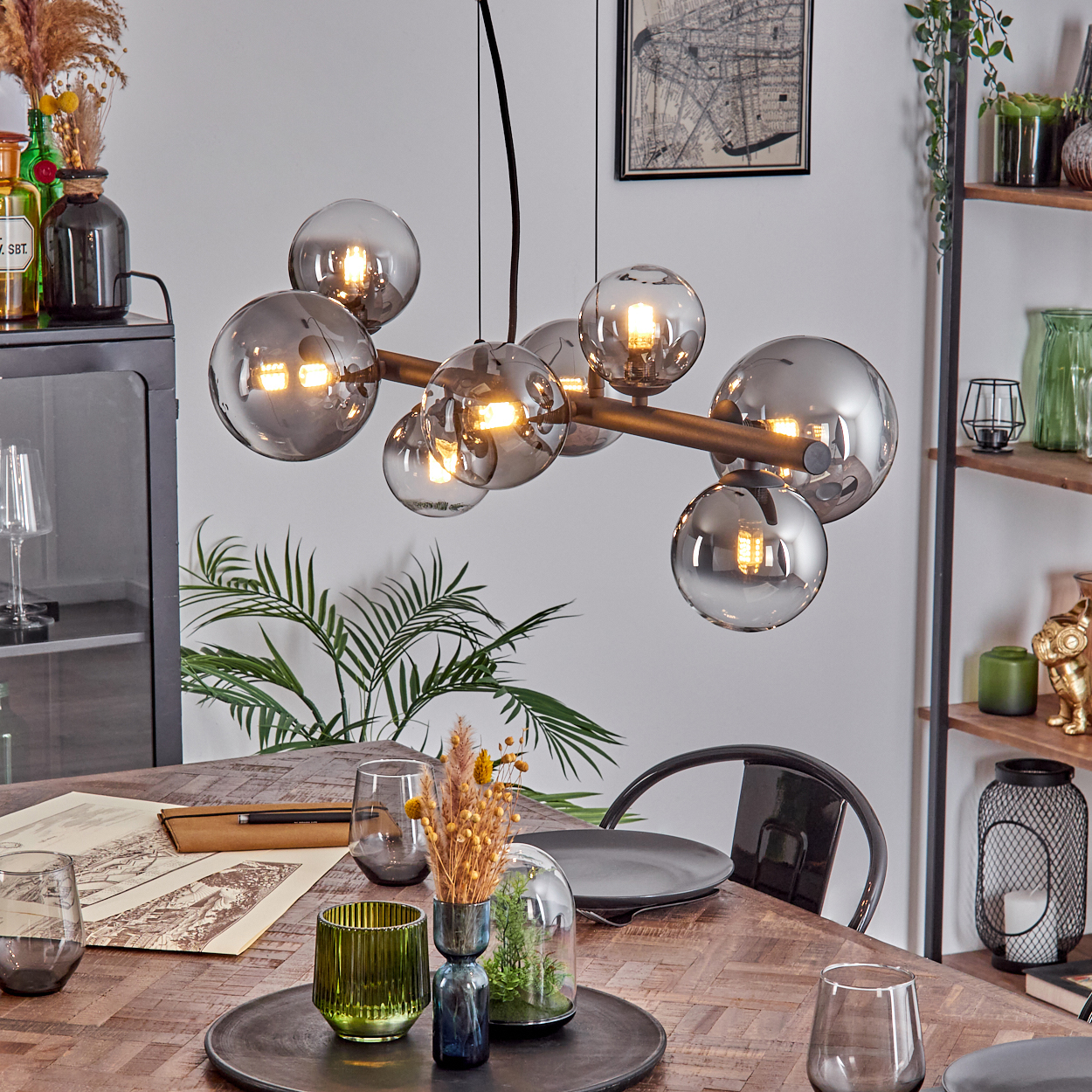 Ein modernes Esszimmer mit Holztisch, Glas-Kugel-Kronleuchter und dekorativen Elementen.