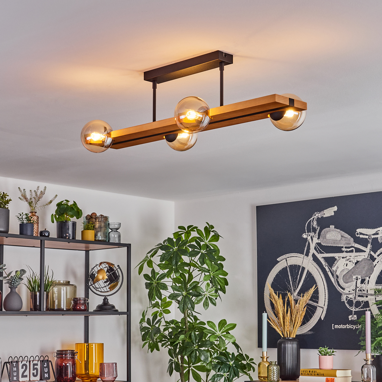 Moderne Deckenleuchte mit vier Glaskugeln. Der Raum hat Pflanzen, Regale mit Dekoration und ein Motorrad-Kunstwerk.