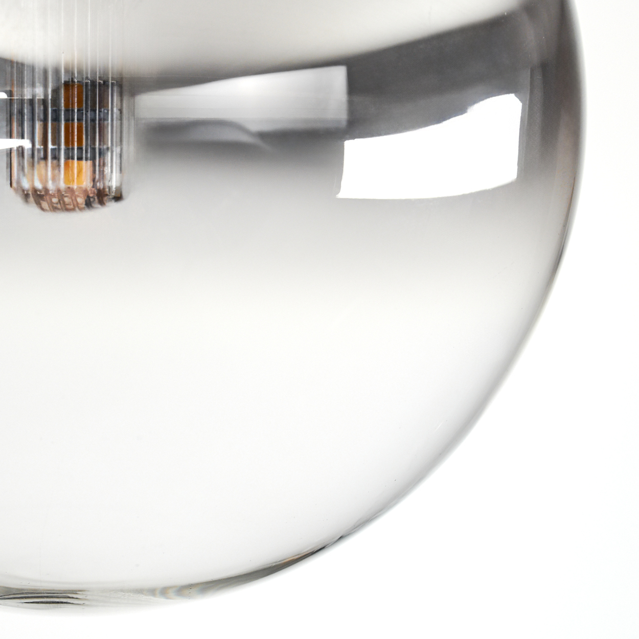 Nahaufnahme einer Glasleuchte. Die klare Glaskugel reflektiert Licht. Im Inneren ist eine metallische Halterung mit Glühbirne zu sehen.