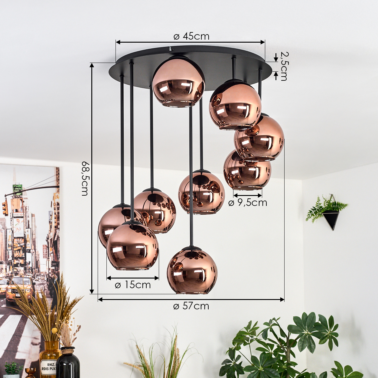 Eine moderne Deckenleuchte mit kupferfarbenen Kugeln hängt an schwarzen Stäben. Abmessungen sind im Bild angegeben. Pflanzen und Dekorationen sind sichtbar.
