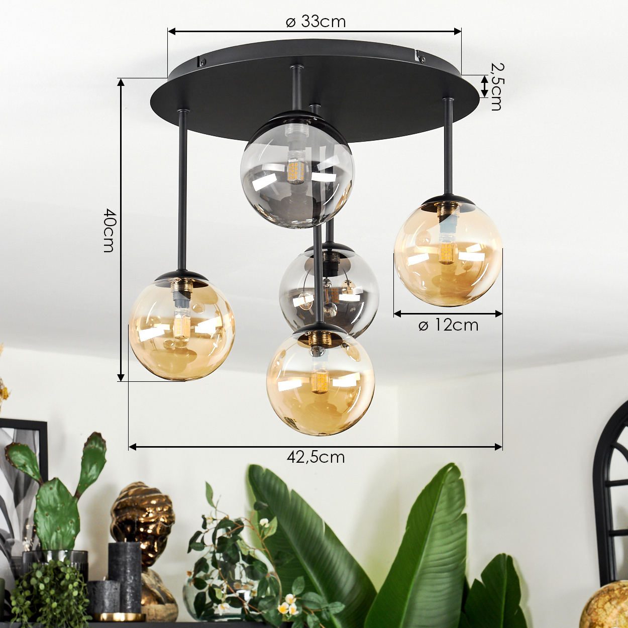 Eine moderne schwarze Deckenlampe mit vier Glaskugel-Schirmen. Maße sind angegeben. Pflanzen und Dekorationen sind im Hintergrund.