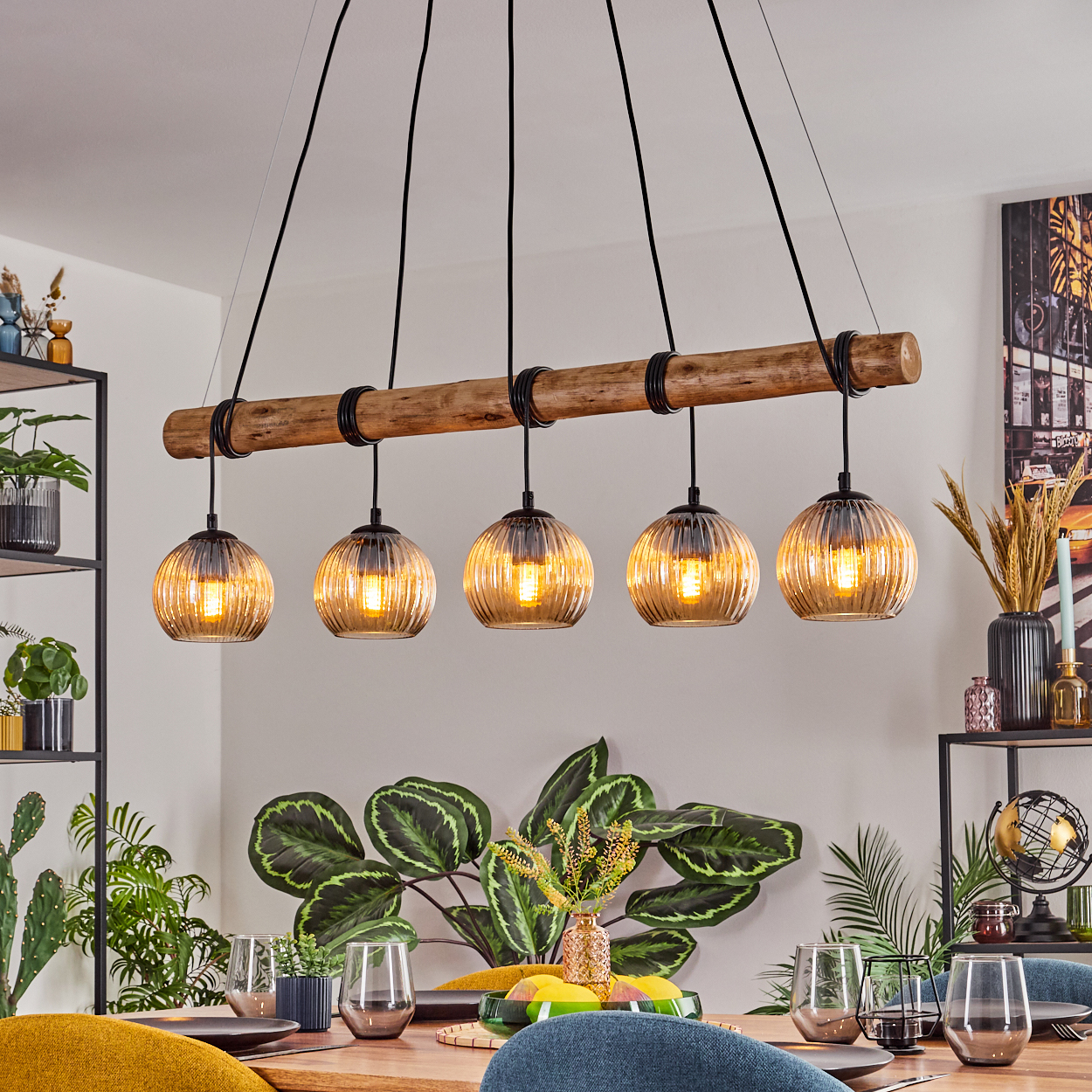 Ein Esszimmer mit Holztisch, Stühlen und einer Hängeleuchte mit fünf Glaslampen.
