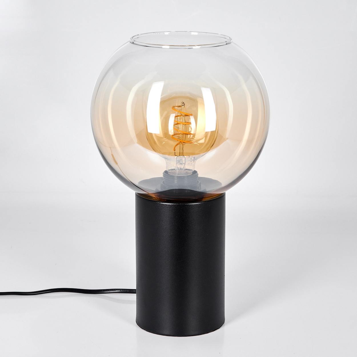 Eine moderne schwarze Lampe mit kugelförmigem, bernsteinfarbenem Glasschirm. Eine Edison-Glühbirne ist darin. Der Sockel ist zylindrisch.