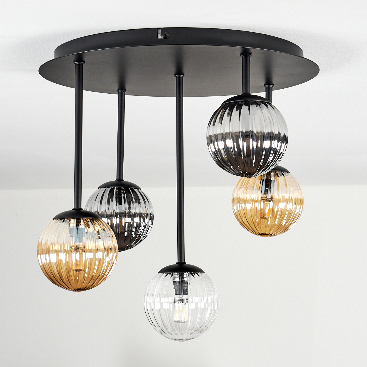 Moderne Deckenleuchte mit fünf Glasschirmen in Bernstein, Klar und Silber, hängend an schwarzen Stangen und einem schwarzen Sockel.