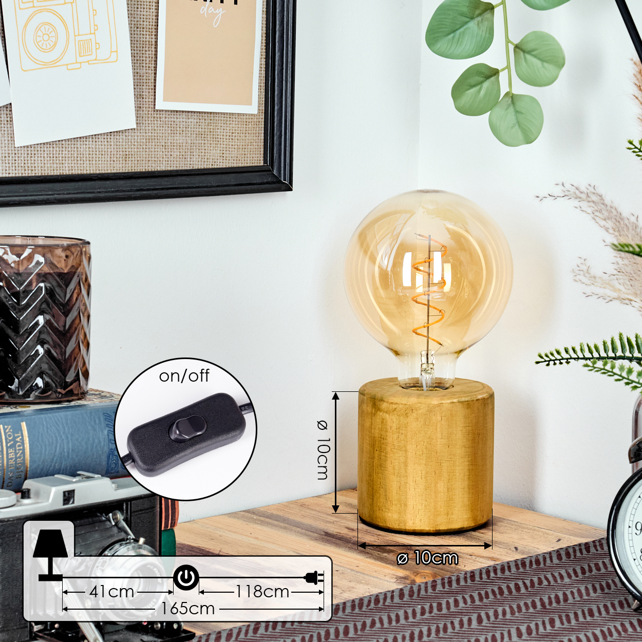 Eine goldene Lampe mit großer Glühbirne steht auf einem Holzsockel. Ein Schalter und Maße sind ebenfalls sichtbar. Im Hintergrund sind eine Uhr, Bücher und Dekoration.