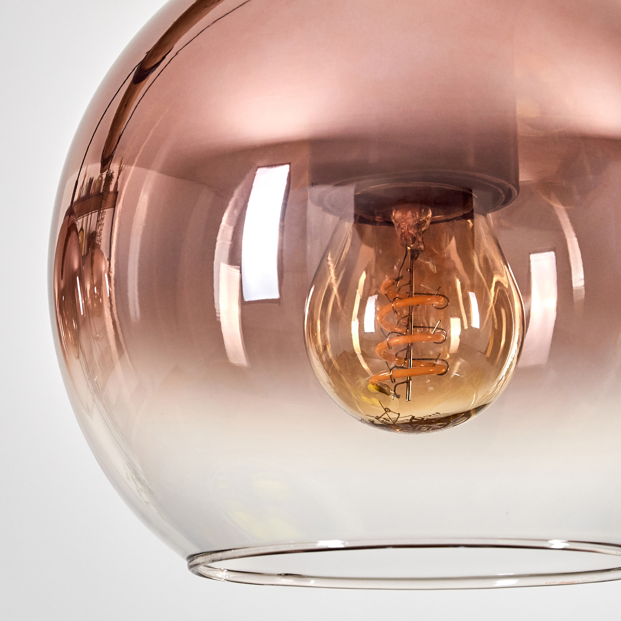 Nahaufnahme einer stilvollen Leuchte. Sie hat einen kugelförmigen, farbverlaufenden Glasschirm mit einer sichtbaren Glühbirne.