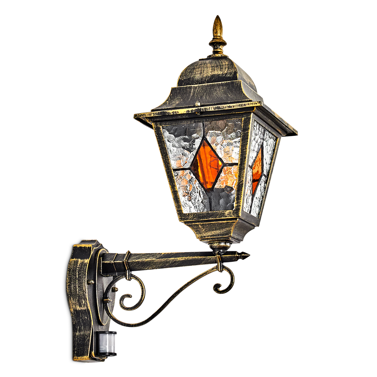 Eine verzierte Außenlampe aus Bronze. Sie hat Glasscheiben mit orangefarbenen Rauten und einen Bewegungssensor. Sie ist an einer Wand befestigt.