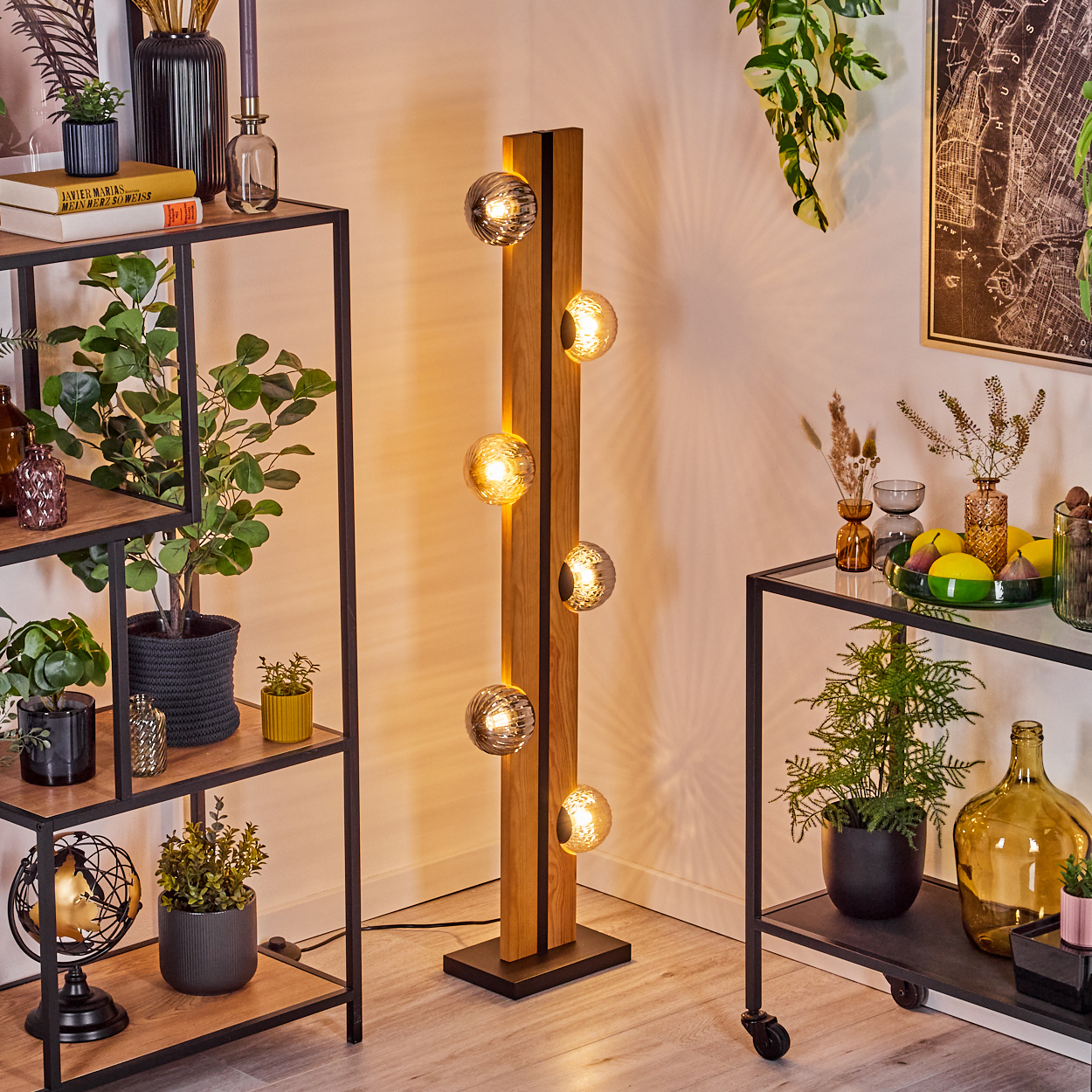 Ein modernes Wohnzimmer mit einer Holzlampe, Regalen mit Pflanzen und Dekorationen und einem Wagen mit einer Pflanze und Früchten.