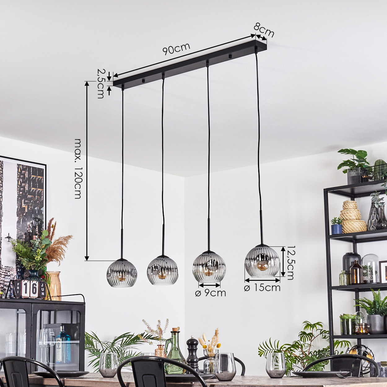 Ein Esszimmer mit einer schwarzen Leuchte mit vier Glas-Hängeleuchten. Ein Tisch und Dekoration sind sichtbar.