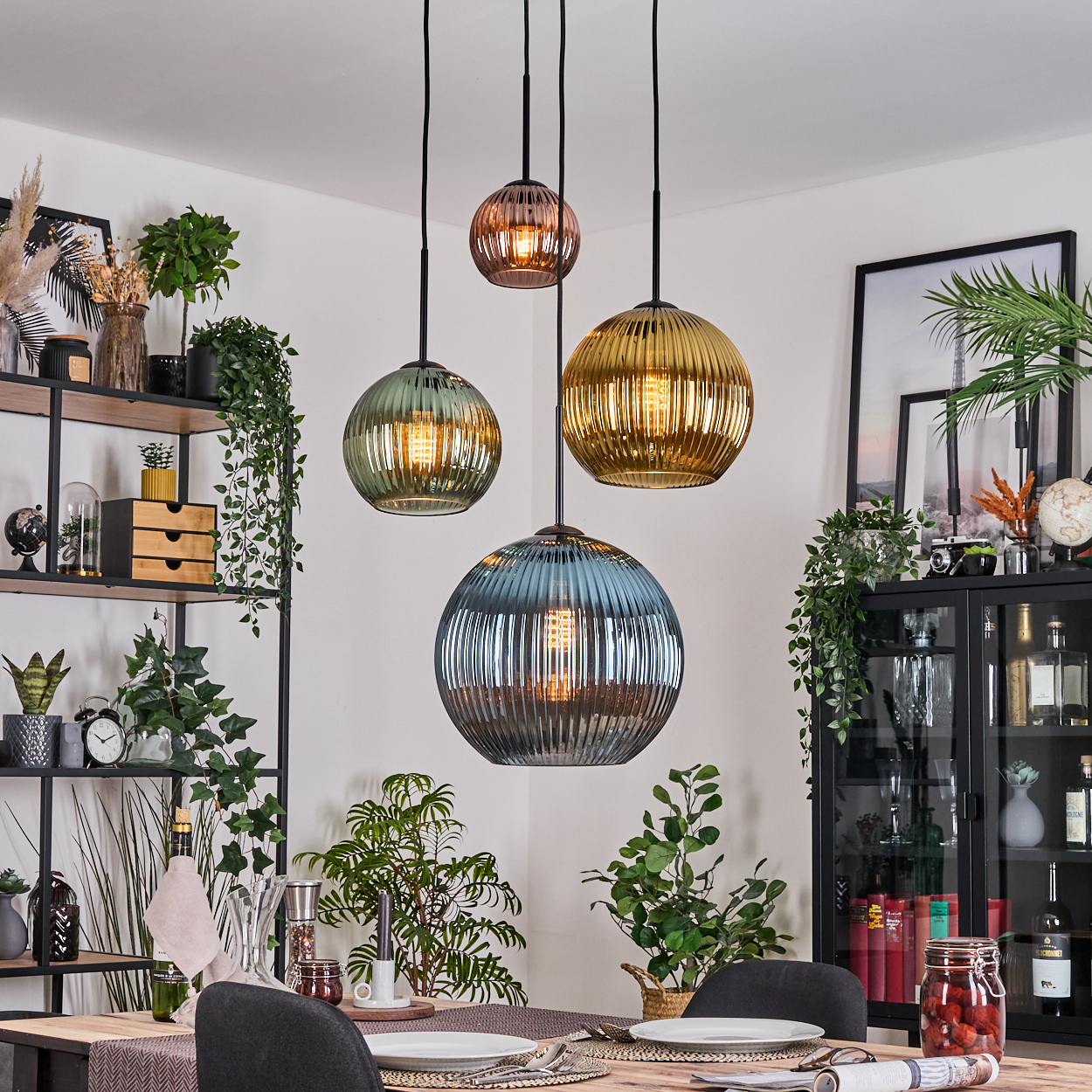 Esszimmer mit vier Glaskronleuchtern. Pflanzen und Dekorationen füllen den Raum, mit einem Tisch, der für eine Mahlzeit gedeckt ist.