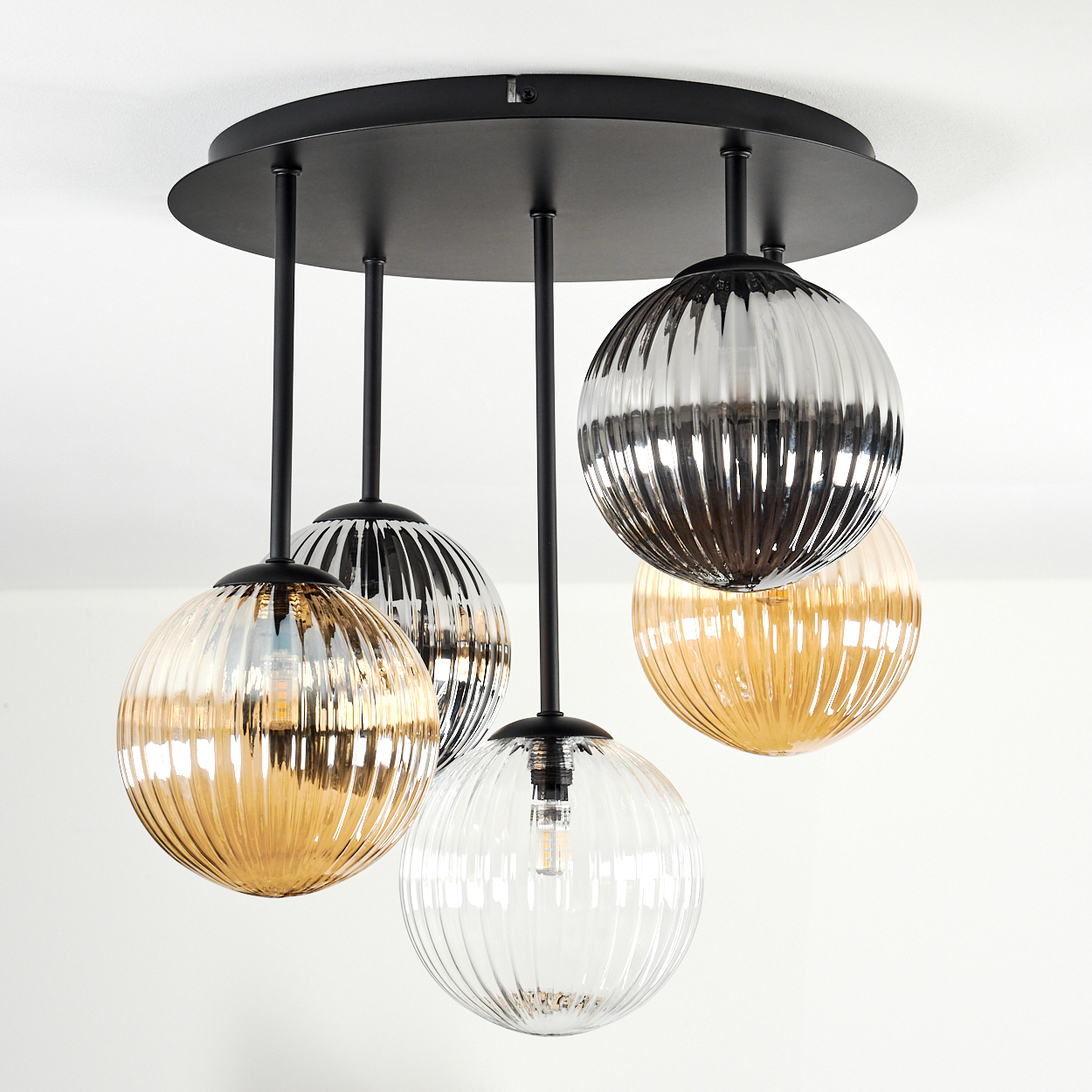 Eine moderne Deckenleuchte mit fünf kugelförmigen Glaslampen, die von einer schwarzen runden Basis hängen. Die Lampen haben gerippte Texturen und verschiedene Farben.