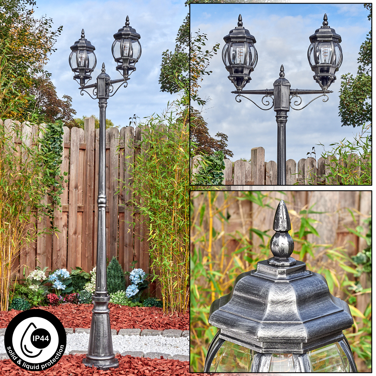 Eine silberne Laterne mit zwei Lichtern steht in einem Garten. Bambus, Holzzaun und Blumen sind im Hintergrund. IP44-Symbol sichtbar.