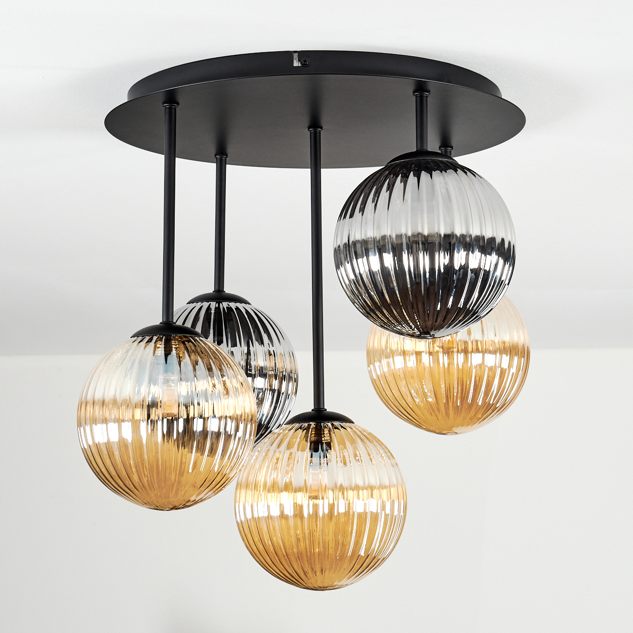 Eine moderne Deckenleuchte mit fünf Glasschirmen. Die Schirme sind gold- und silberfarben und hängen an einer schwarzen runden Basis.