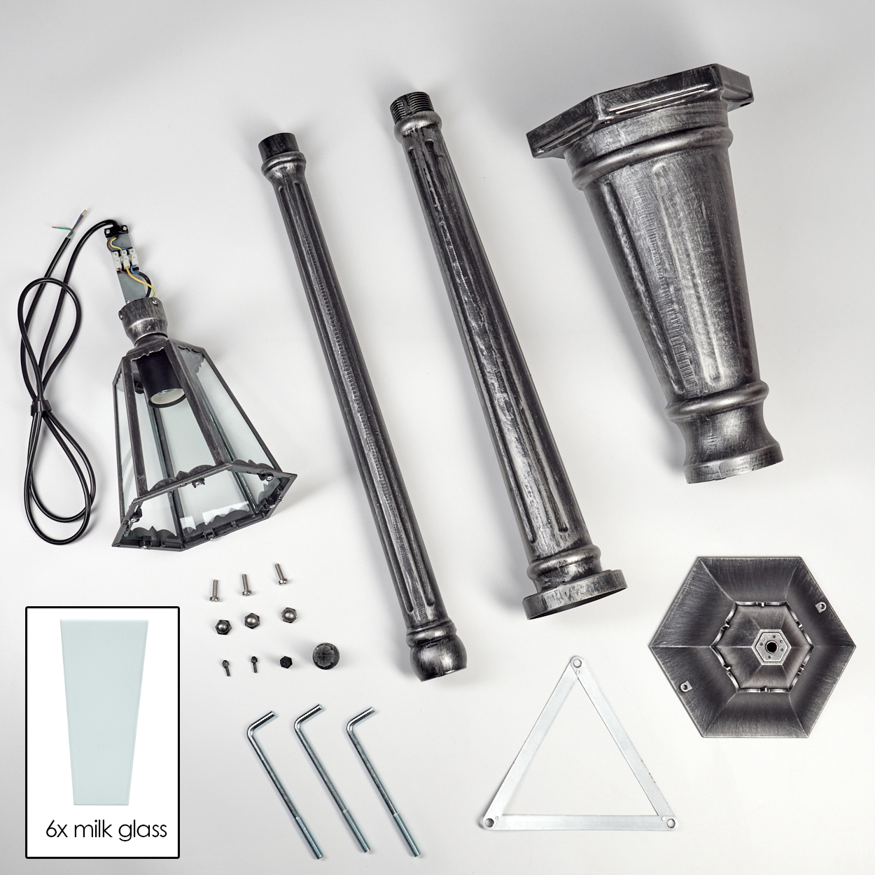Zerlegte Lampenteile auf weißem Untergrund: Lampenschirm, Stangen, Sockel, Glas, Schrauben und Werkzeuge. Grau- und Silberfarben.